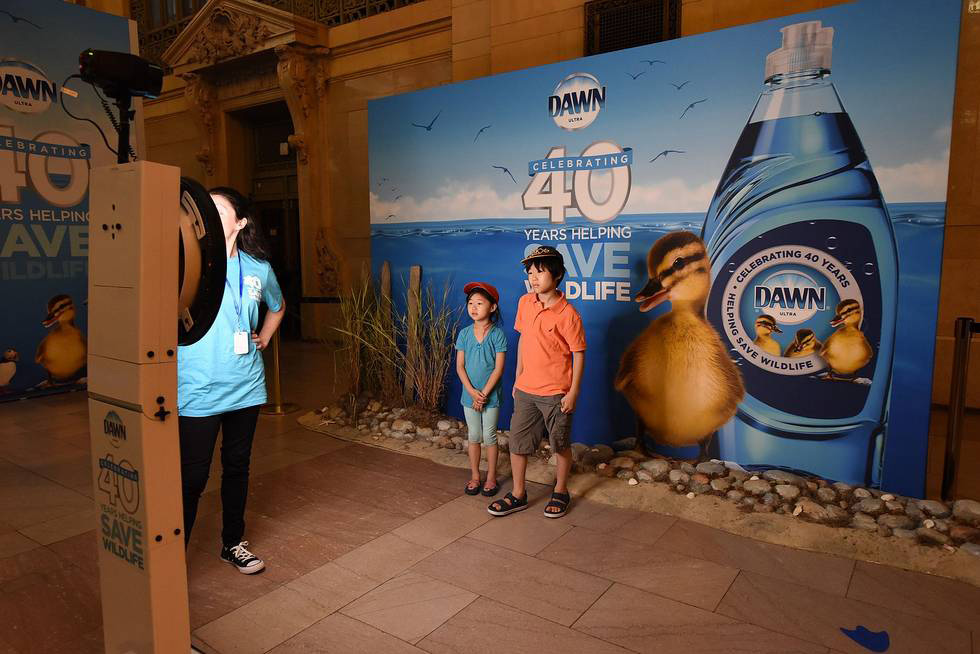 Children pose for a photo next to a branded wall at Dawn's Grand Central celebration.
